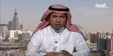 A man wearing a white thobe and red-and-white checkered ghutra sits in front of a cityscape with modern buildings. The logo of Al Arabiya is visible in the top right corner.