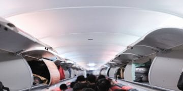مسافرين يرتبون حقائب السفر داخل الصندوق العلوي للطائرة.